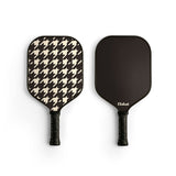 Two pickleball paddles, one with a houndstooth pattern and the other black, on a white background.