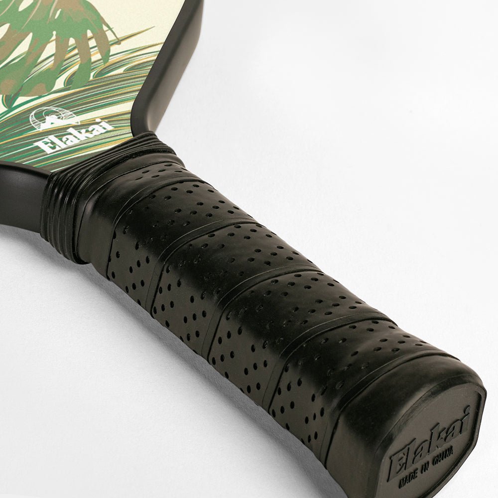 Close-up of a pickleball paddle with a black grip and visible brand name on a light gray background.