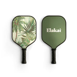 Two pickleball paddles, one with a tropical leaf design and the other with 'Elakai' branding, on a white background.