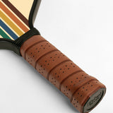 Close-up of a tennis racket handle with brown leather grip and striped strings on a white background