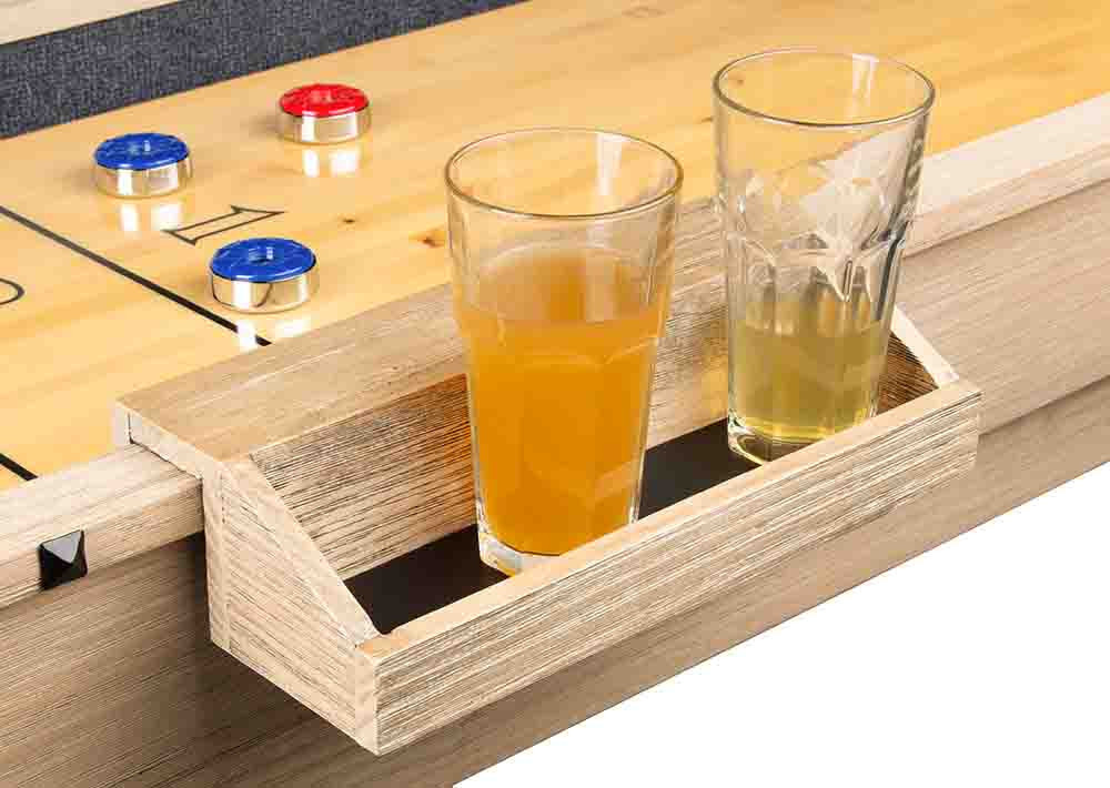 Two glasses of beer on a shuffleboard table with scoring cups.