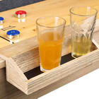 Two glasses of beer on a shuffleboard table with scoring cups.