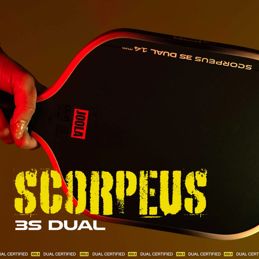 Hand holding a red ping pong paddle with 'SCORPEUS 3S DUAL' branding on a brown background