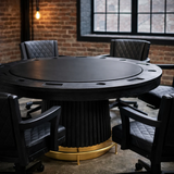 Black poker table with gold base in a room with brick walls and large windows.