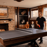 Family playing ping pong in a home entertainment room with a fireplace and bookshelf.