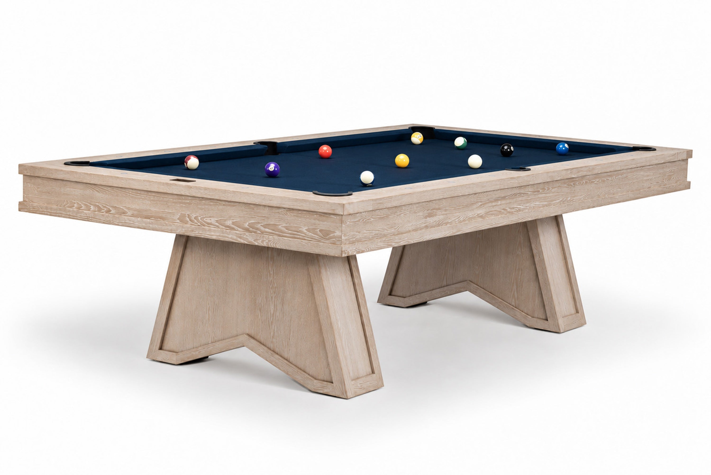 A modern pool table featuring a light natural wood frame and legs, paired with a dark navy blue felt surface and several colorful billiard balls, shown against a plain white background.