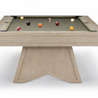 A modern pool table with a light oak wood frame and a dark green felt surface, shown on a clean white background with several billiard balls scattered on the table.