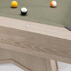 Close-up of a wooden pool table showing the light oak frame, green felt surface, and several billiard balls on a white background.