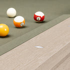 Close-up of a pool table corner with four billiard balls on a green felt surface and a light wood grain rail.