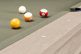 Close-up of a pool table corner with four billiard balls on a green felt surface and a light wood grain rail.