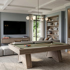 A modern pool table in a spacious, contemporary home bar and living room setting with a sectional sofa, TV, bookshelves, and a wine cooler.