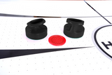 Two black strikers and a red puck on the Hathaway Brentwood 7.5-Ft Air Hockey Table.