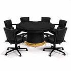 Black round table with gold base surrounded by black office chairs on a white background
