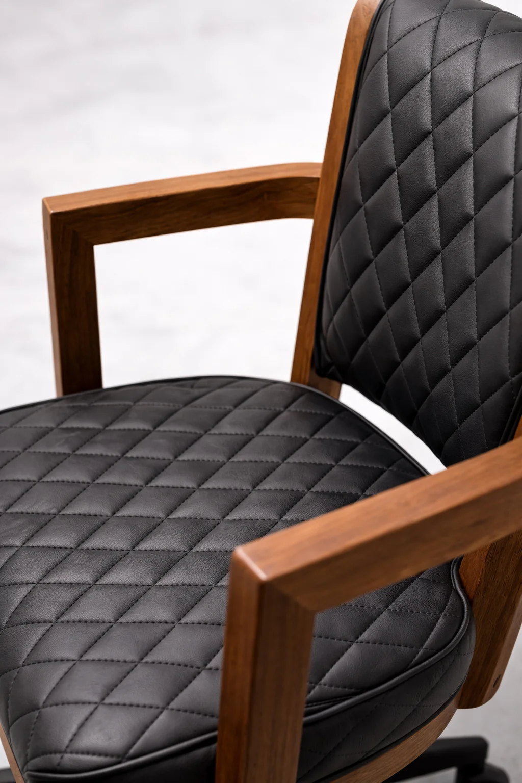 Chair with black quilted cushions and wooden armrests on a white background