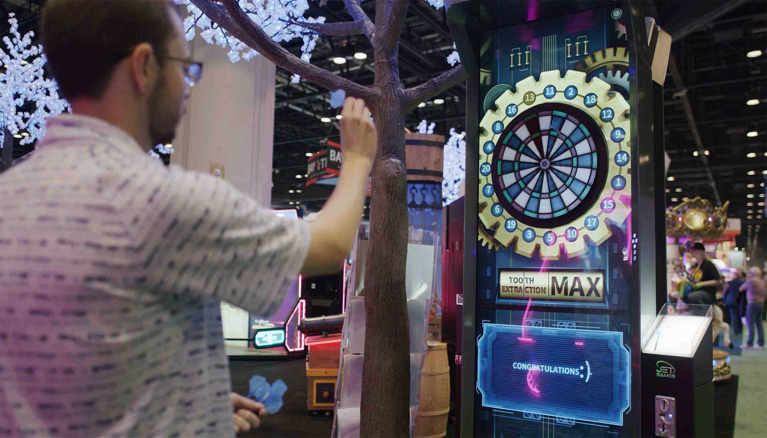 Man interacting with a digital dartboard game at an indoor event.