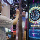 Man interacting with a digital dartboard game at an indoor event.