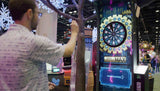 Man interacting with a digital dartboard game at an indoor event.