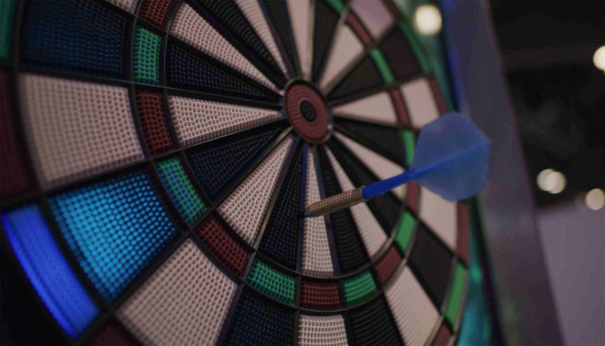 Dart hitting a target with colorful sections on a dark background