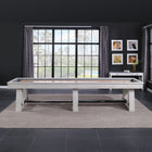 A Playcraft 16' Yukon Pro-Style Shuffleboard Table in Northern Drift in a modern room with windows.