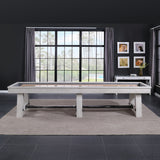 A Playcraft 16' Yukon Pro-Style Shuffleboard Table in Northern Drift in a modern room with windows.