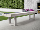 American Heritage Lanai 9' Outdoor Shuffleboard Table in Pearl White on patio with flowers.