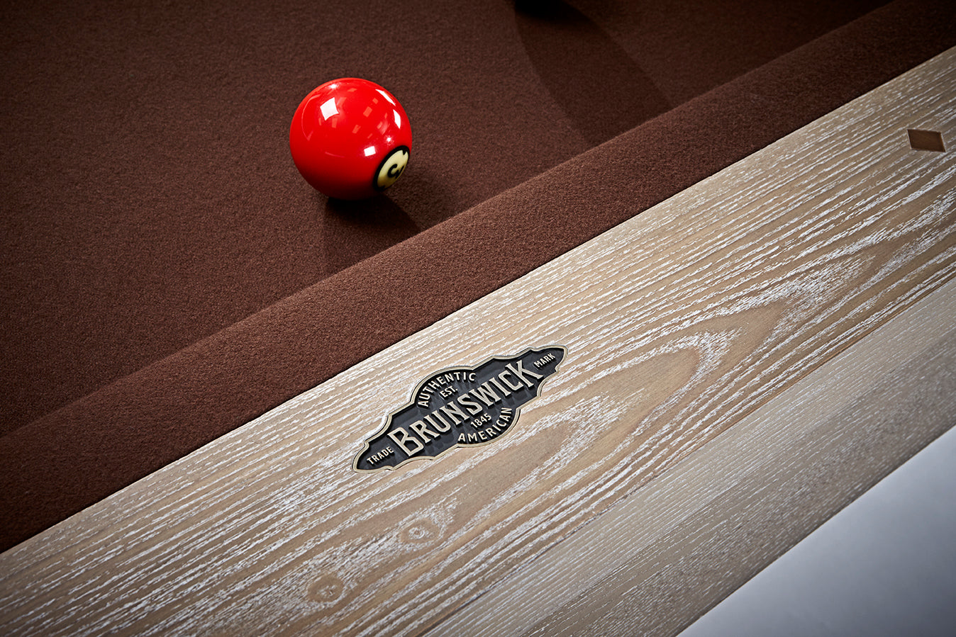 A red billiard ball on a Brunswick Billiards Matanza 8' Slate Pool Table in Sandwashed.