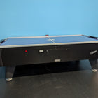 A Dynamo 8' Pro Style Home Air Hockey Table with electronic scorekeeper stands by a blue wall.