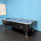 Dynamo 8' Pro Style Home Air Hockey Table by Dynamo in a blue room with black floor and window.
