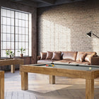 A game room with a Brunswick Billiards Parsons 8' Pool Table, air hockey, sofa, and large windows.