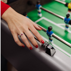 Hand with red nail polish and a ring on a foosball table