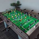 Table football game with players on a green field, indoors.
