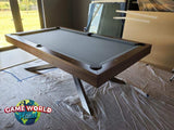 A wooden pool table with a dark gray felt surface, photographed in an indoor room with construction debris and plastic sheeting on the floor. A 'Game World Planet' logo is visible in the lower-left corner.