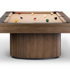 A modern pool table with a thick rectangular wood frame and a cylindrical ribbed wood base, shown on a clean white background with several billiard balls on the tan felt surface.