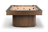A modern pool table with a thick rectangular wood frame and a cylindrical ribbed wood base, shown on a clean white background with several billiard balls on the tan felt surface.