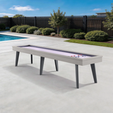 Outdoor shuffleboard table in a backyard setting with a pool and fence in the background.