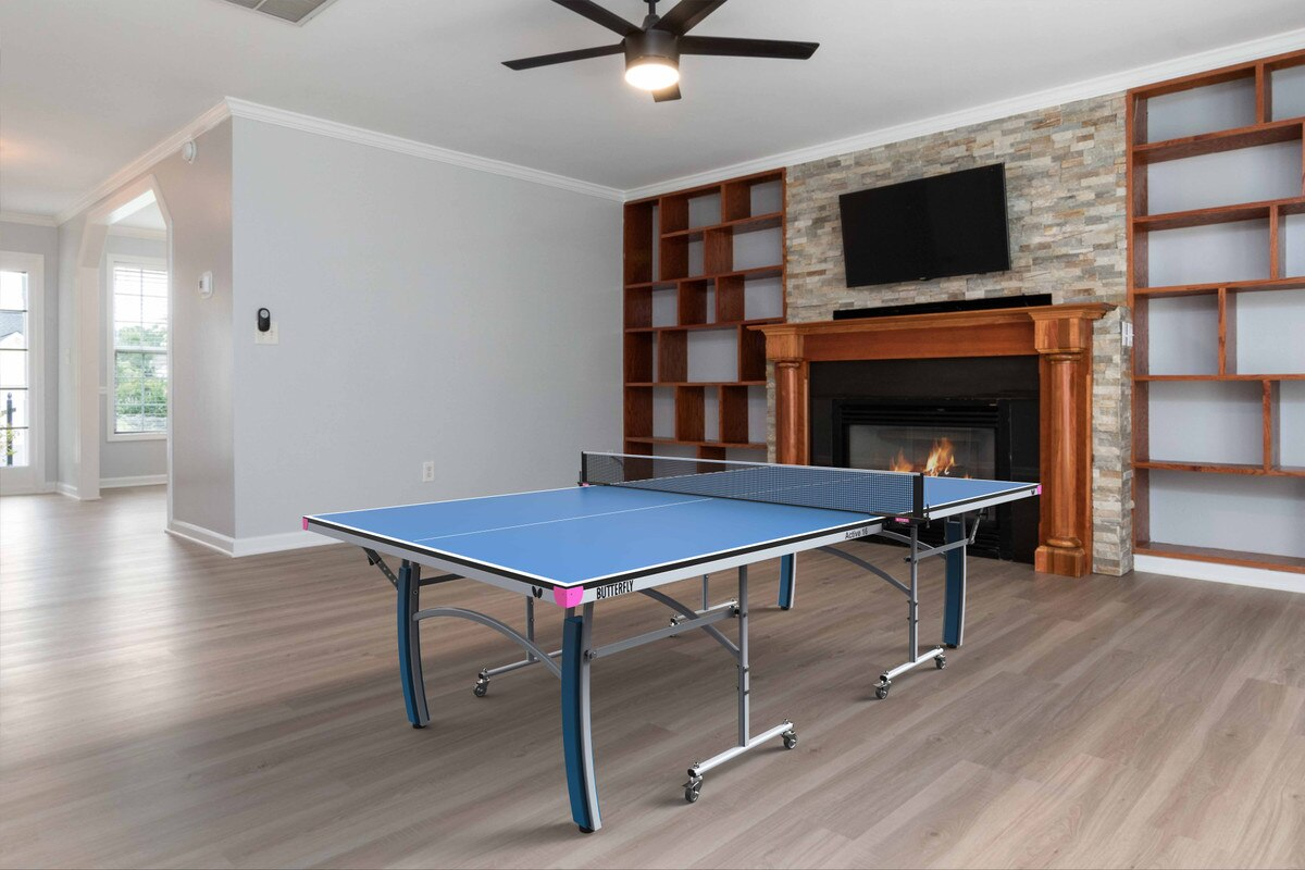 A Butterfly Active 16 Table Tennis Table set up in a bright indoor space, showcasing its sleek blue playing surface, sturdy frame, and adjustable legs. 