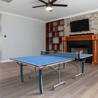 A Butterfly Active 16 Table Tennis Table set up in a bright indoor space, showcasing its sleek blue playing surface, sturdy frame, and adjustable legs. 