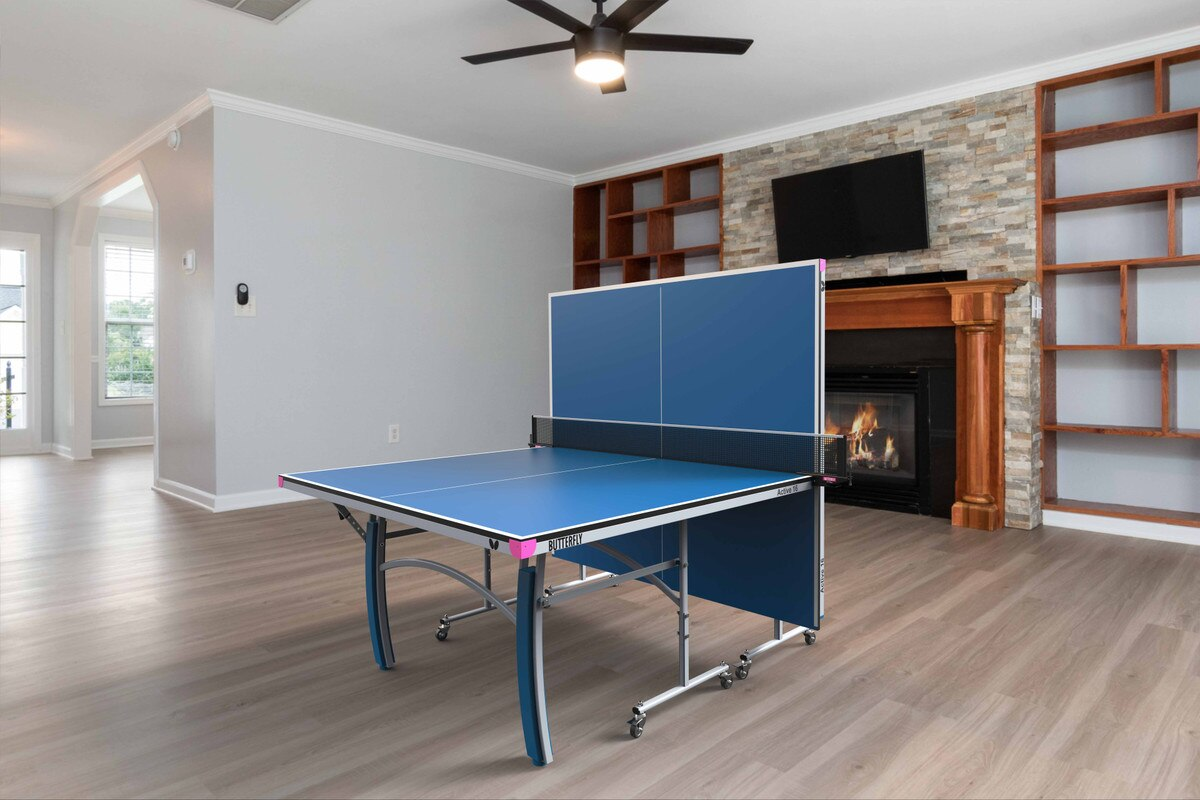 A Butterfly Active 16 Table Tennis Table set up in a bright indoor space, showcasing its sleek blue playing surface, sturdy frame, and adjustable legs. 