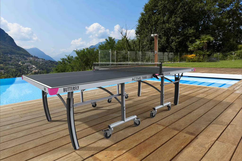 Butterfly outdoor ping pong table on a wooden deck with a pool and scenic background