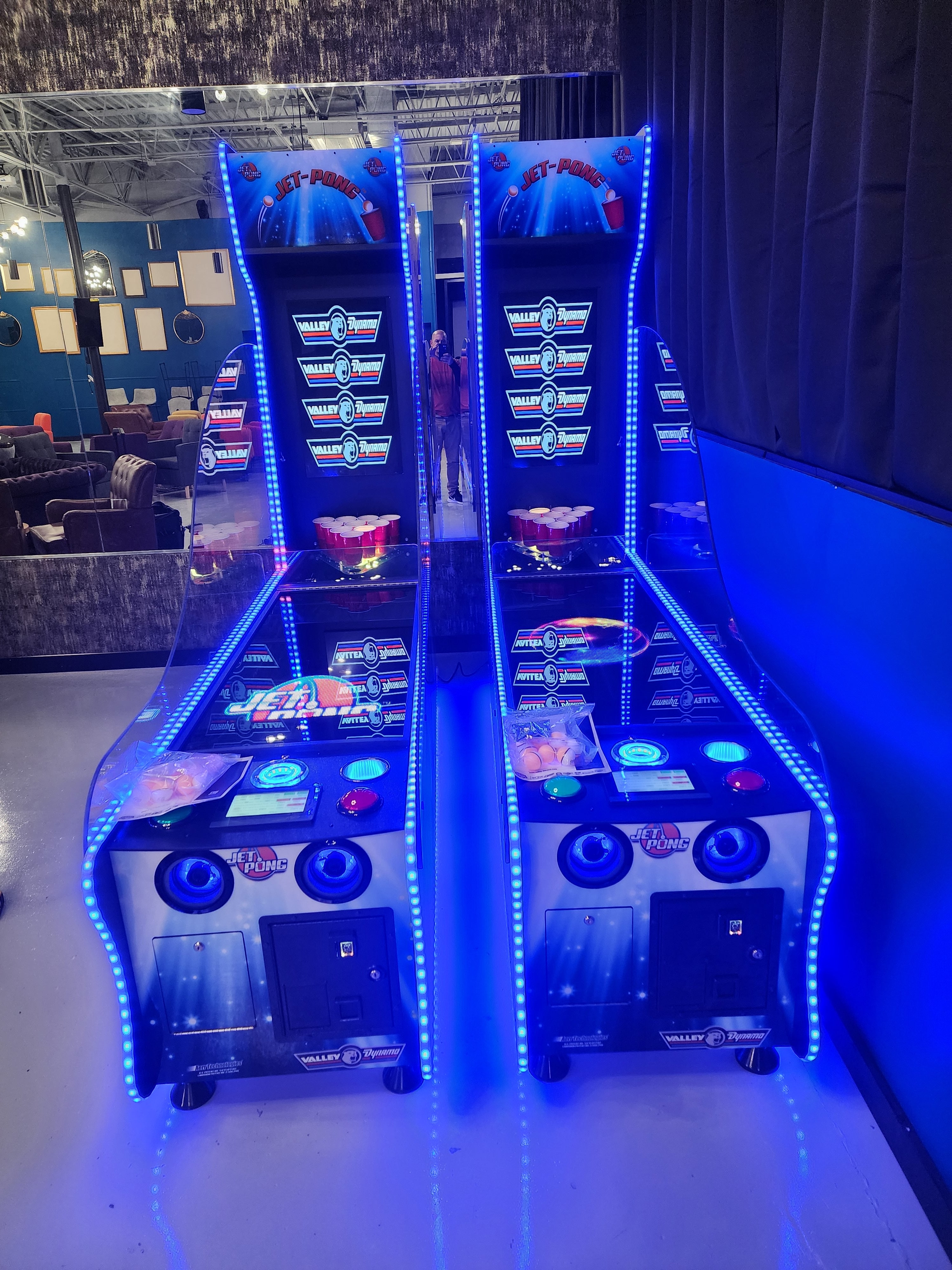 Two Valley Jet-Pong machines by Valley glow blue in a game room.