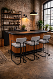 Bar area with wooden counter and stools in a brick-walled room.
