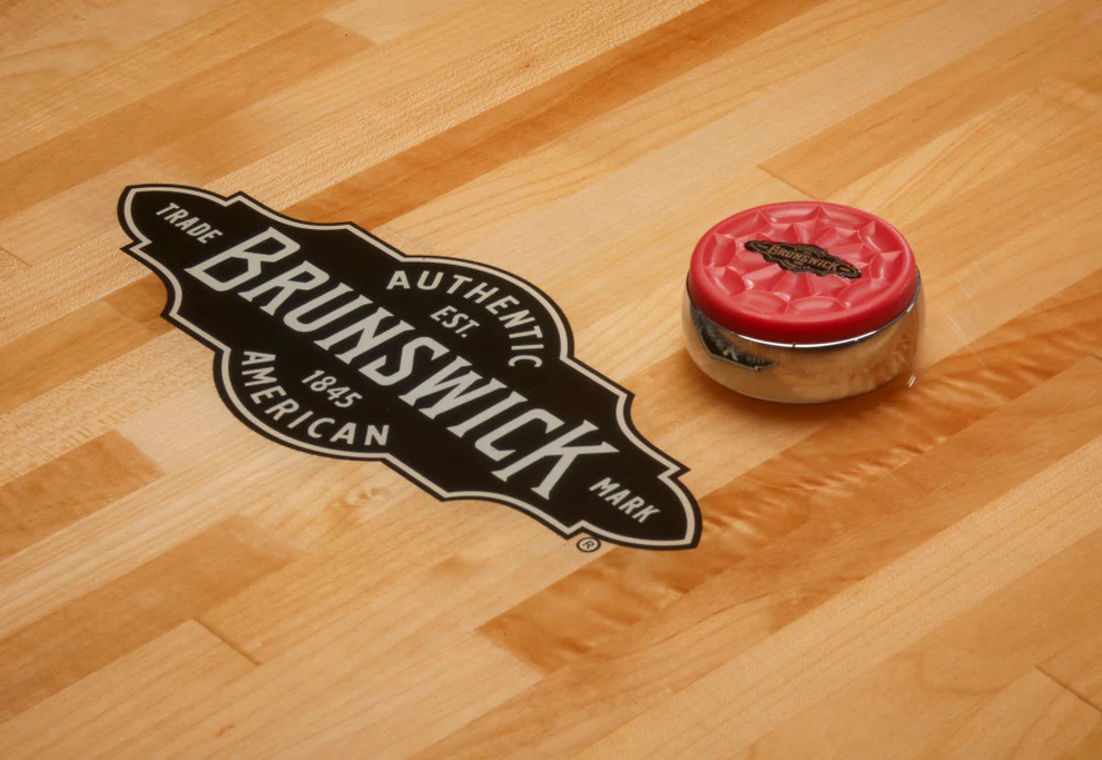A puck on the Brunswick Billiards Botanic 12' Shuffleboard Table in Rustic Dark Brown.