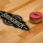 A puck on the Brunswick Billiards Botanic 12' Shuffleboard Table in Rustic Dark Brown.