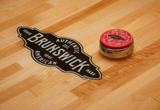 A puck on the Brunswick Billiards Botanic 12' Shuffleboard Table in Rustic Dark Brown.