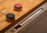 Two pucks on a Brunswick Billiards Botanic 12' Shuffleboard Table in Rustic Dark Brown.