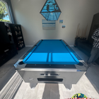 Pool table with blue felt in a room with a lamp and window.