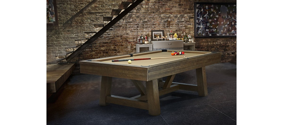 Brunswick Billiards Botanic 8' Pool Table with balls and cues in a rustic game room.