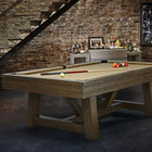 Brunswick Billiards Botanic 8' Pool Table with balls and cues in a rustic game room.