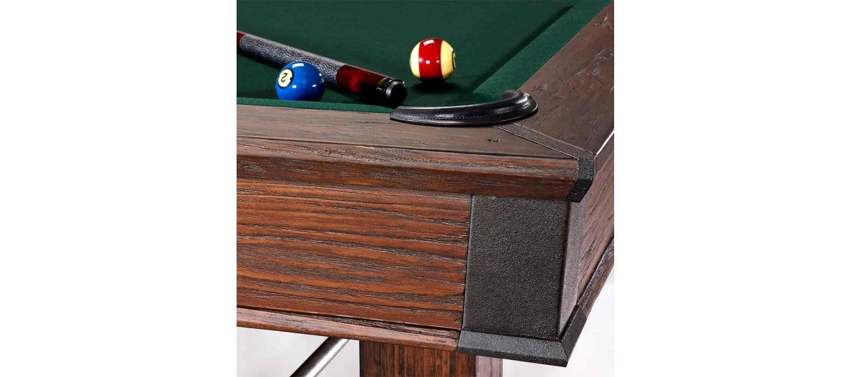 Close-up of Brunswick Billiards Canton 7' Pool Table in Black Forest with balls and cue near pocket.