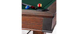 Close-up of Brunswick Billiards Canton 7' Pool Table in Black Forest with balls and cue near pocket.